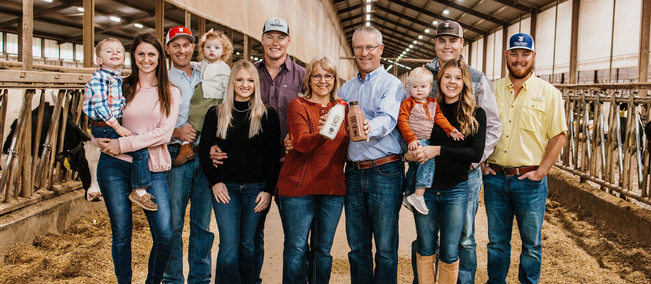 A Family of dairy farmers poses for a group photo, and the people range in age from toddler to elder.